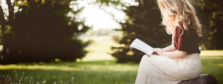 Vrouw leest bijbel in de natuur
